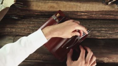 Erkek ressam deri çantayı aletler, fırçalar ve palet bıçağıyla açar.