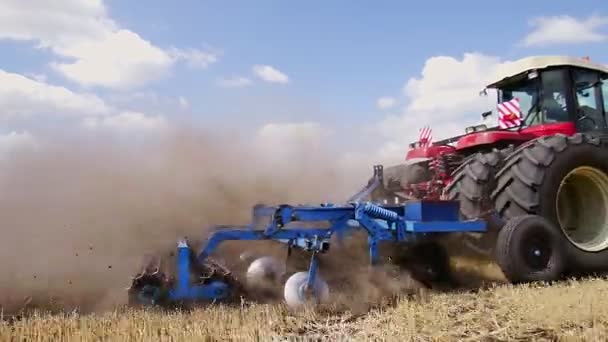 Fermier sur un tracteur rouge labourant le sol aride poussiéreux. La voiture de ferme est suivie par les oiseaux affamés. L'agro-industrie au printemps — Video