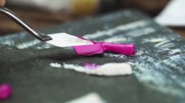 Ressam boya palet bıçağıyla boya renklerini karıştırıyor.