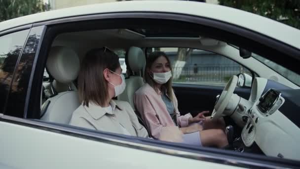 Αγελάδες νεαρές γυναίκες κάθονται στο αυτοκίνητο με ιατρικές μάσκες στα πρόσωπα για να αποφευχθεί η εξάπλωση COVID-19. — Αρχείο Βίντεο