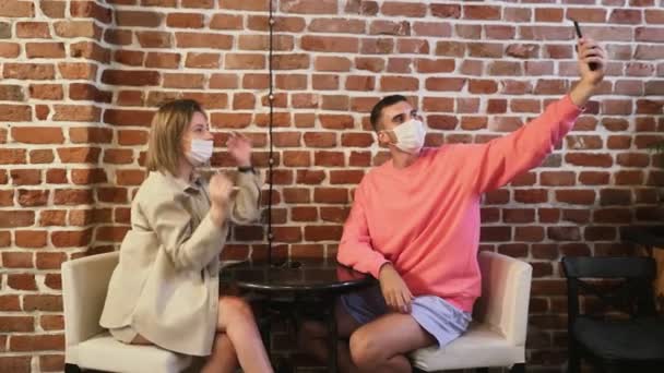 Молода пара бере селфі в кафе, чекаючи на їх замовлення — стокове відео