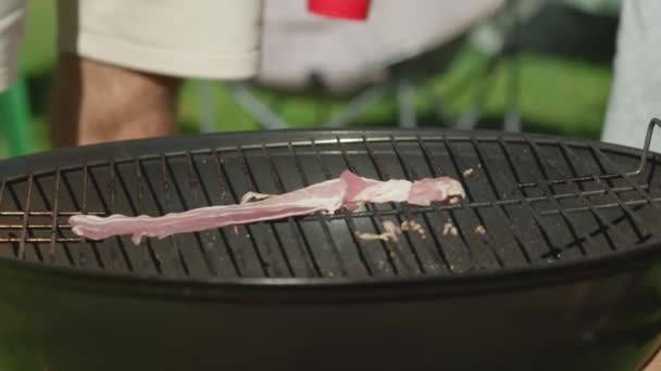 Rodina griluje slaninu na mřížce. Přátelé jsou o víkendu na táboře. — Stock video