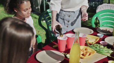 Genç mutlu kadın dışarıda kağıt bardaklara soda dolduruyor.
