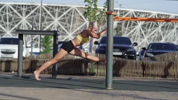 Zijaanzicht van atletische vrouw is strekt zich uit en zit op de binddraad — Stockvideo