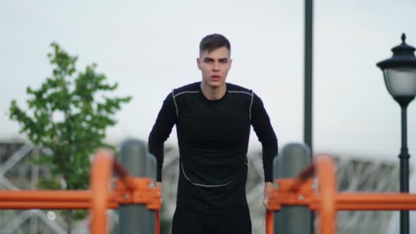 A fiatalember megáll a vízszintes korláton, miközben a városi parkban edz.. — Stock videók