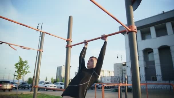Seitenansicht eines jungen muskulösen Mannes bei Muscle Up-Übungen an der Bar im Freien — Stockvideo