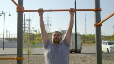 Kıdemli sporcu yatay bir çubuğa asılır ve bacaklarını kaldırır.