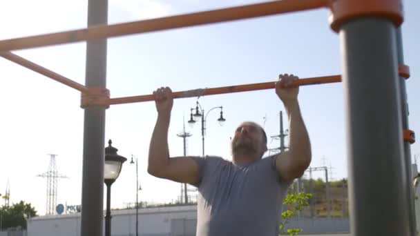 Hombre deportivo senior haciendo flexiones en el entrenamiento horizontal al aire libre — Vídeos de Stock