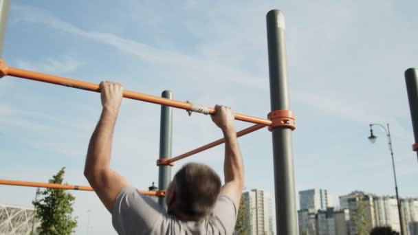 Senior homme faisant pull ups sur l'entraînement horizontal à l'extérieur — Video