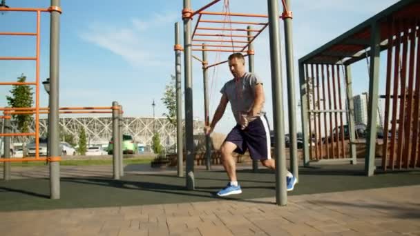 Ein älterer muskulöser Mann macht im Freien Ziehübungen mit Gummiband. Training — Stockvideo