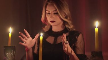 Dişi falcı sihirli mumun üzerinde ellerini hareket ettiriyor.
