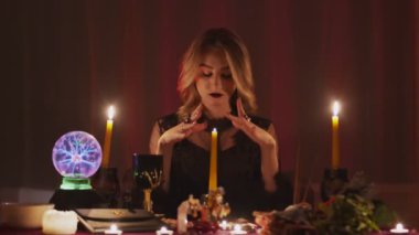 Dişi falcı sihirli mumun üzerinde ellerini hareket ettiriyor.