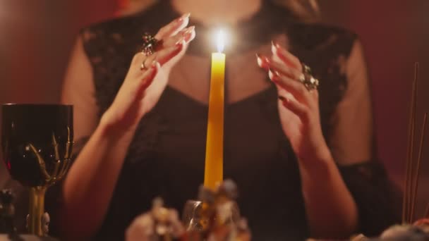 Соберите женщину-гадалку, двигающую руками над волшебной свечой — стоковое видео