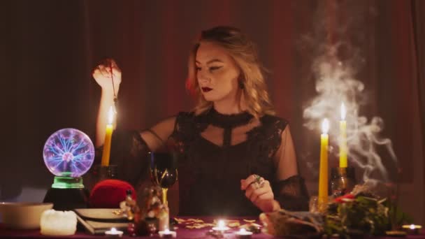 Жіночий плакат, що тримає чарівний маятник над свічкою — стокове відео