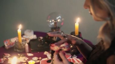 Falcı cadı bir gülün yapraklarını toplayıp sihirli bardağa atıyor.