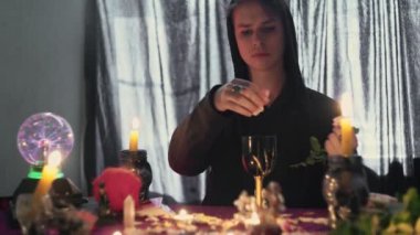 Erkek falcı bir gülün yapraklarını toplayıp sihirli bir cama fırlatıyor.