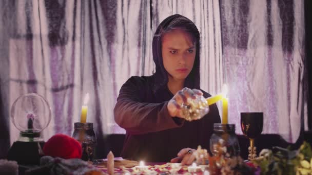 Male sorceress psychic lights a candle for rituals — Stock Video