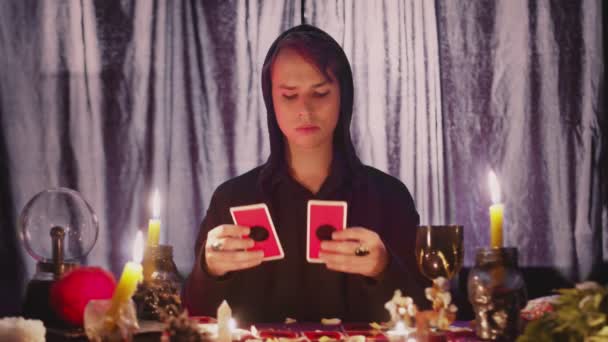 Мужчина гадалка читает оккультные карты Таро и перемещает их по свече — стоковое видео