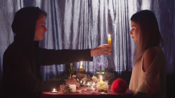 Boční pohled na věštkyně muž pohybuje svíčka v blízkosti obličeje mladé ženy klienta — Stock video