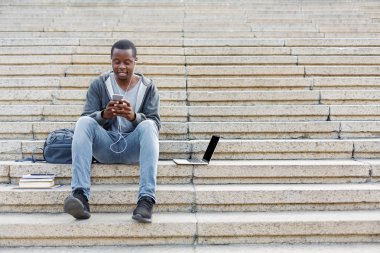 Merdivenlerde oturan ve smartphone kullanarak öğrenci