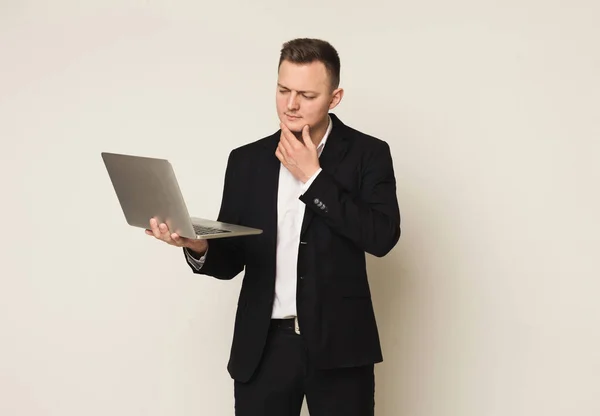 Pensativo joven caucásico hombre de negocios utilizando el ordenador portátil —  Fotos de Stock