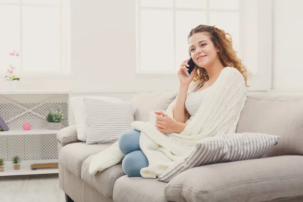 Uma casa acolhedora. Menina em cobertor com telefone móvel — Fotografia de Stock