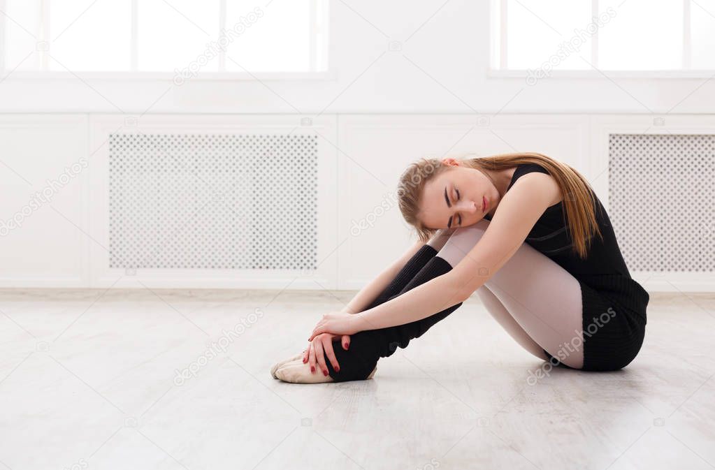 Classical ballet dancer sitting in white training class