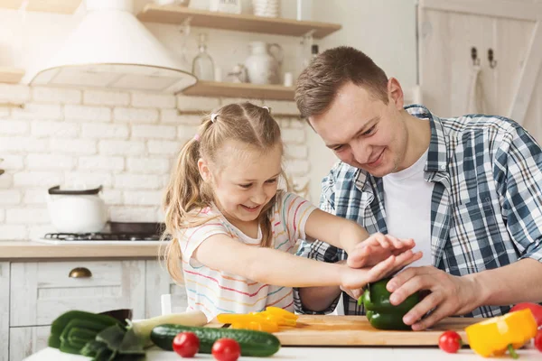Little girl and dad having fun while cooking in kitchen
