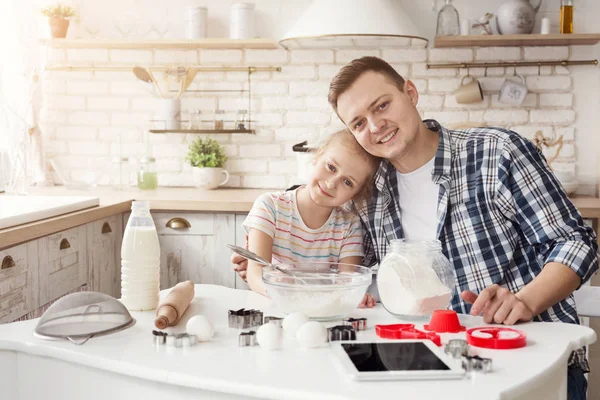 Father and daughter reading cake recipe on digital tablet