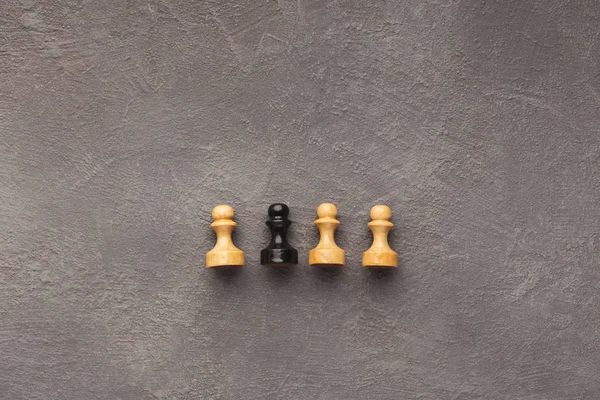 Line of white pawns with one black inside — Stock Photo, Image