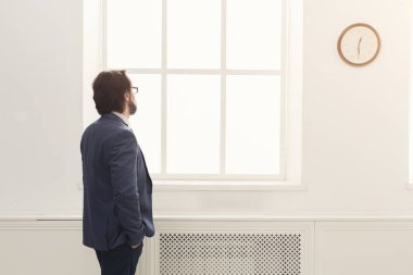 Saat ofiste bakarak iş adamı. Arkadan görünüm