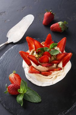 Siyah arka plan üzerine çilek ile lezzetli Anna Pavlova beze pasta