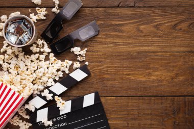 Klaket, film makaraları ve ahşap arka plan, üstten görünüm üzerinde patlamış mısır