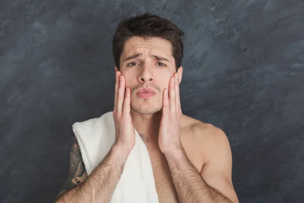 Handsome young tattooed man touching his face