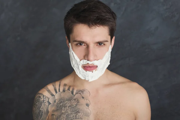 Серьезный татуированный мужчина с пеной на лице — стоковое фото