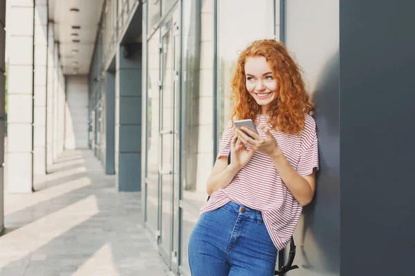 Mujer joven feliz utilizando el teléfono inteligente al aire libre — Foto de Stock
