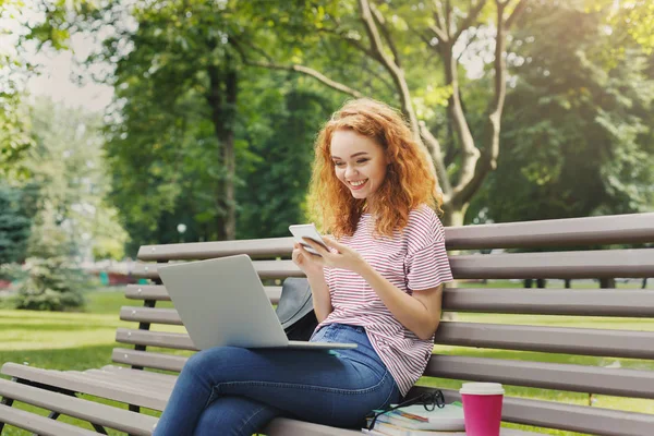 Mujer feliz mensajes de texto en el teléfono inteligente en el parque — Foto de Stock