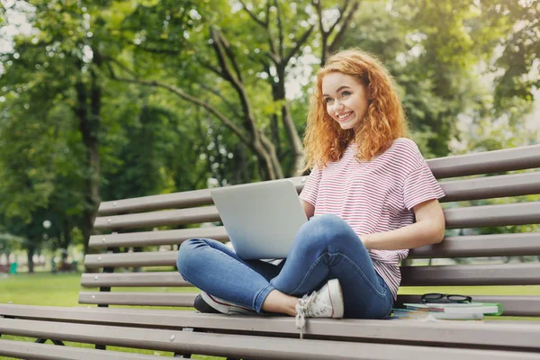 Mujer feliz está utilizando el ordenador portátil en el parque — Foto de Stock