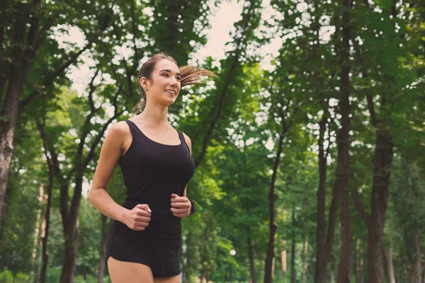 Mujer joven corriendo en el parque verde, espacio para copiar — Foto de Stock