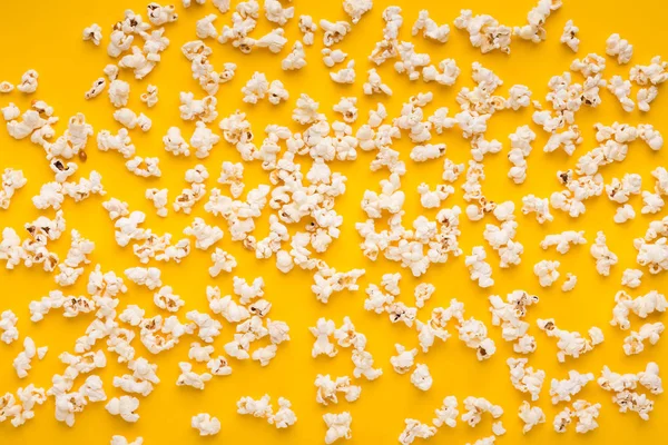 Slaty popcorn scattered on yellow background, top view — Stock Photo, Image