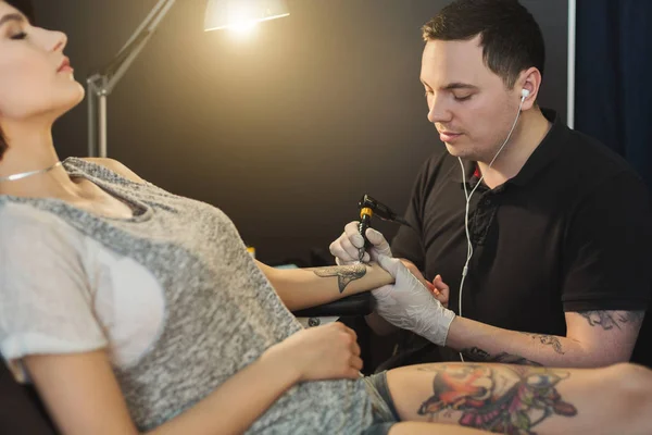 Tattoo artist working with needle on clients arm