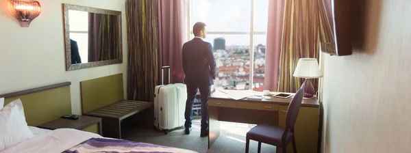 Joven hombre de negocios con equipaje en la habitación de hotel —  Fotos de Stock