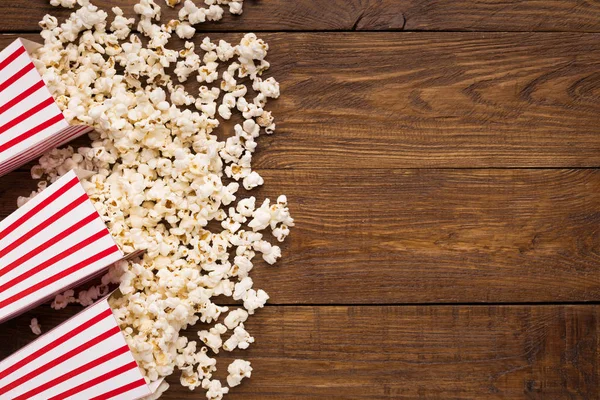 Hink med popcorn på trä bakgrund, ovanifrån — Stockfoto