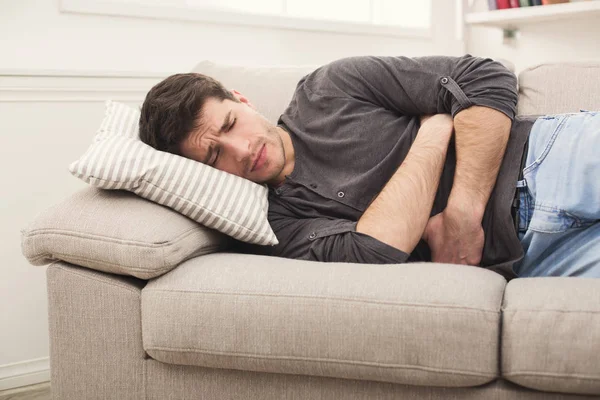 Junger Mann mit Bauchschmerzen zu Hause — Stockfoto