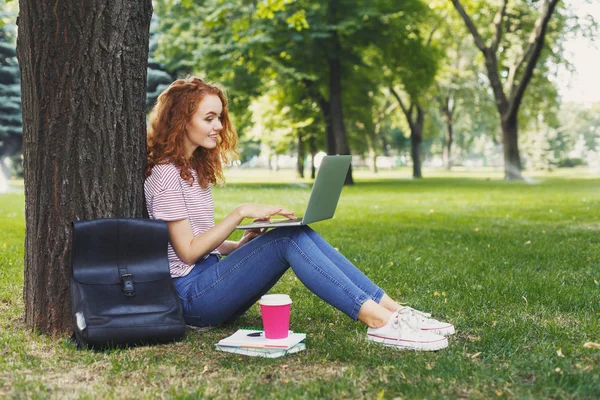 Mujer joven feliz usando el ordenador portátil en el parque — Foto de Stock