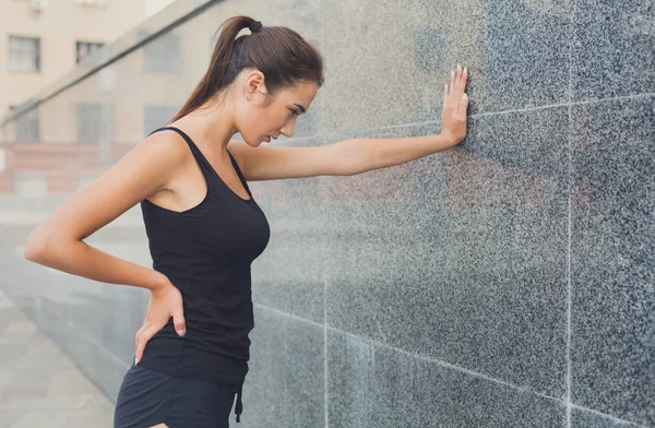 Žena běžec má přestávku, opřel se o stěnu — Stock fotografie