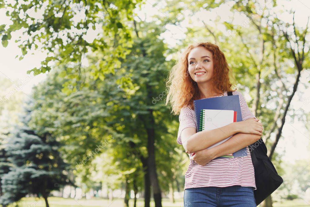 Smiling student girl with books in park outdoors