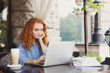 Açık havada laptop ile çalışan genç Kızıl saçlı kadın serbest meslek