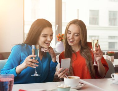 Şampanya ve kafede smartphone ile mutlu kadın arkadaşlarıyla