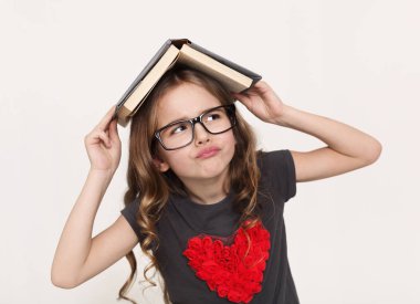 Başında beyaz arka plan üzerinde kitapla düşünceli küçük kız